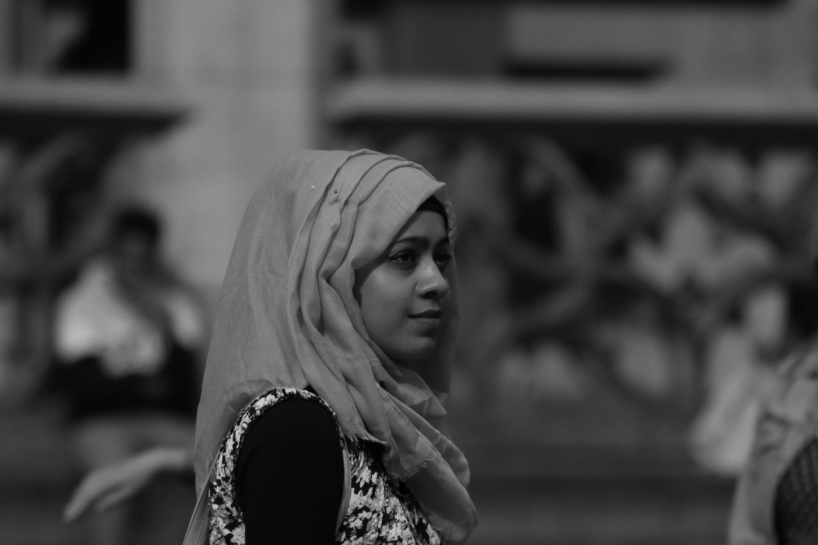 Black and white portrait of a woman in hijab on a busy street in Brussels.