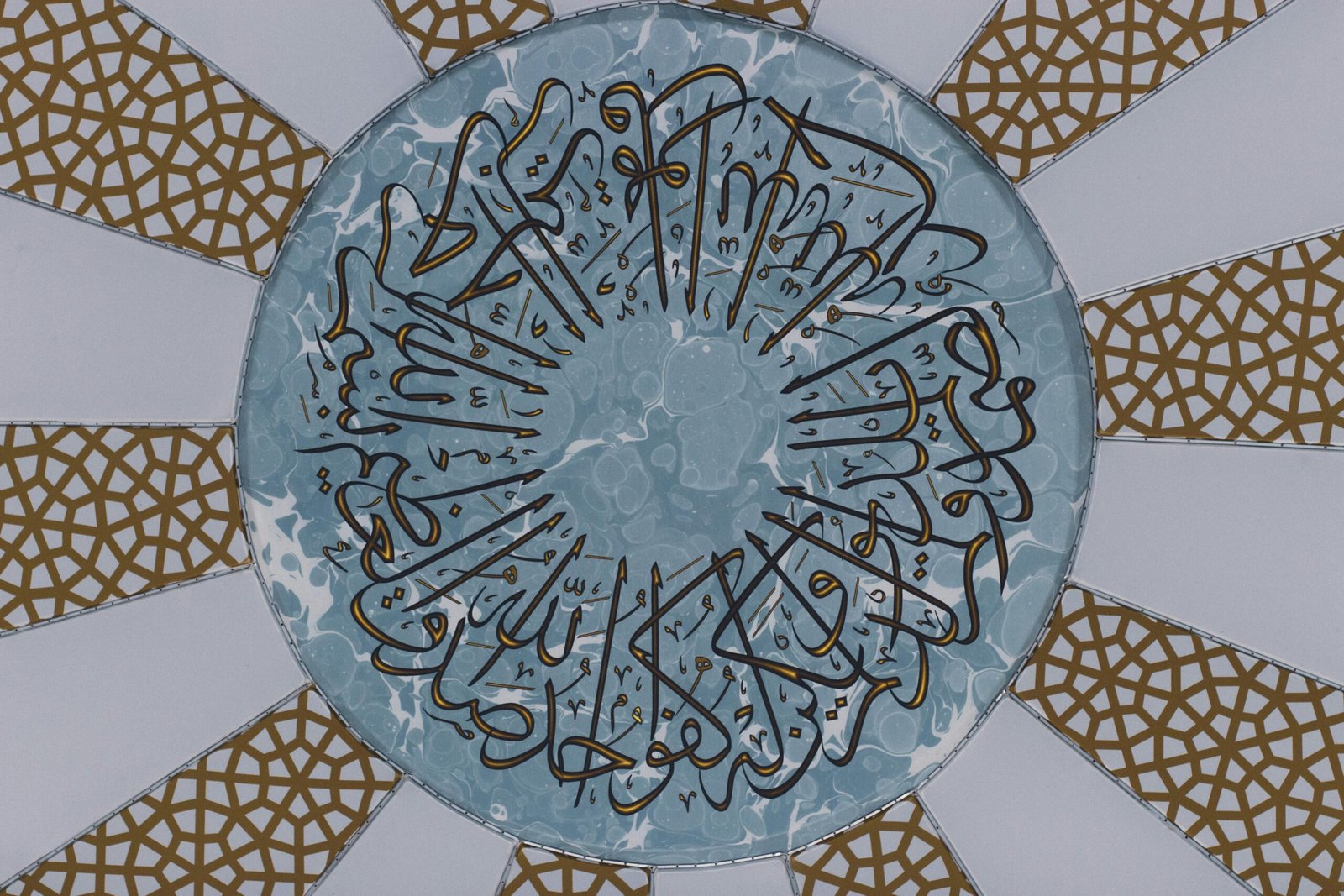 Intricate Arabic calligraphy featured on a geometric dome ceiling with gold patterns.